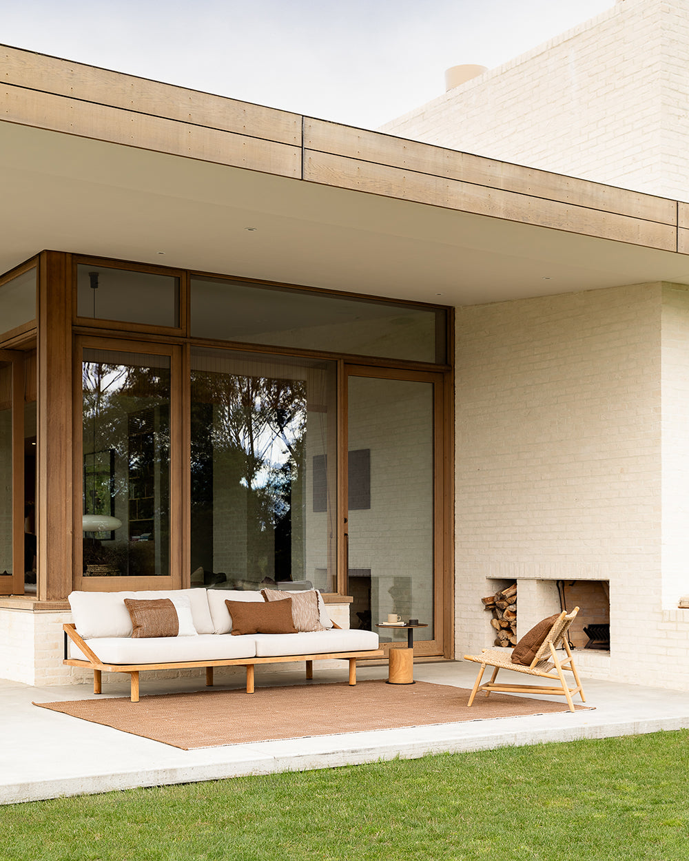 Modern outdoor living space with a sofa, chairs, and a fireplace.