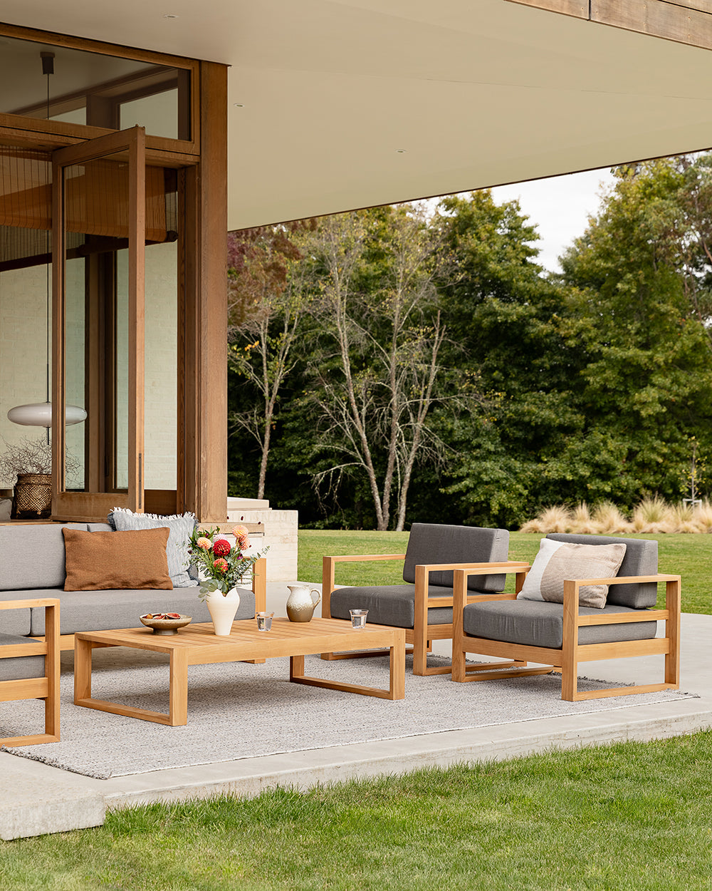 Outdoor patio set with wooden furniture and cushions on a patio area.