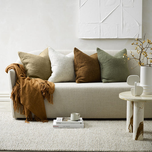 Cyprian Cushions in sage, oatmeal, treacle and white on a cream linen couch with a white rug and white wall art