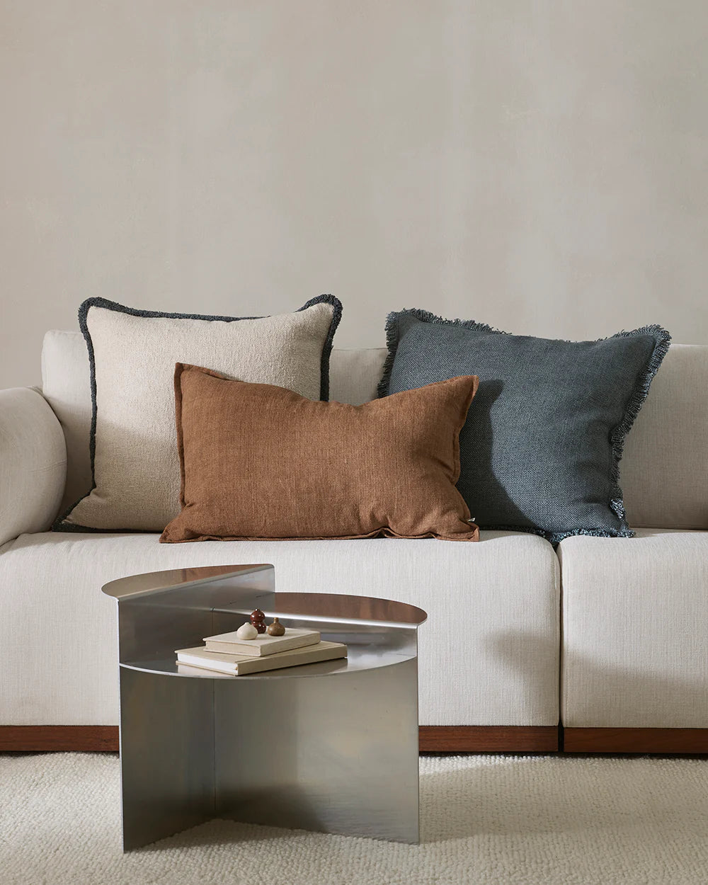 White sofa with decorative pillows and a small metallic coffee table in a living room setting.
