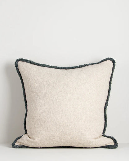 Beige pillow with black textured border on a light gray background