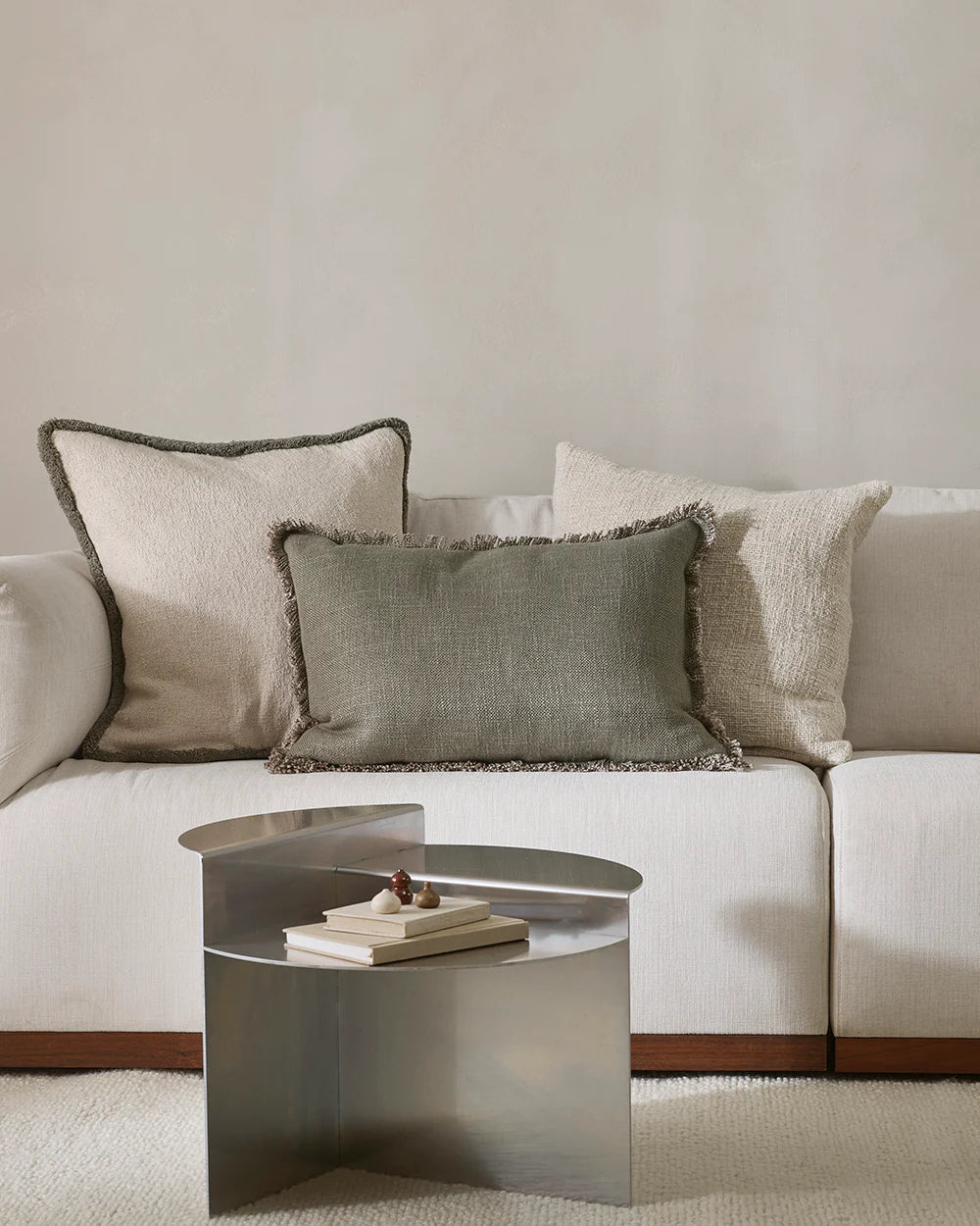 White sofa with decorative pillows and a metallic coffee table in a living room setting.