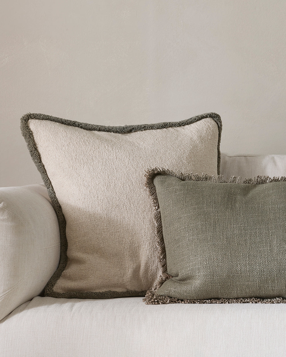Two textured pillows on a sofa against a neutral background