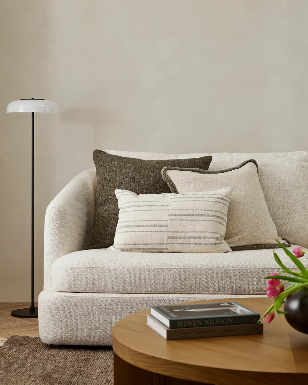 Beige sofa with decorative pillows in a living room setting.