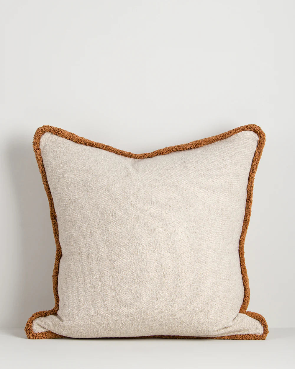 Beige pillow with brown trim on a light gray background