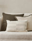 Three pillows on a beige sofa against a neutral wall