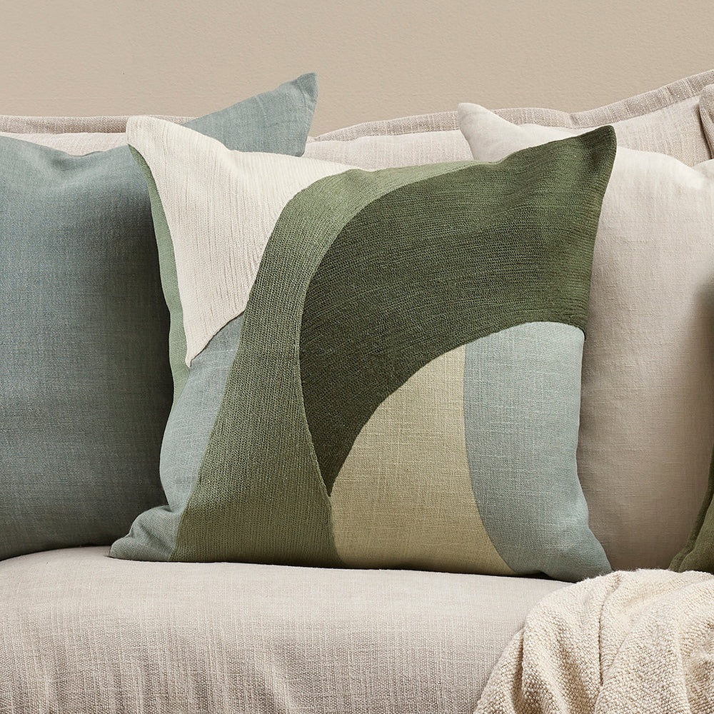 Decorative pillows in greens and blues on a sofa with a focus on color and design. Mid century style