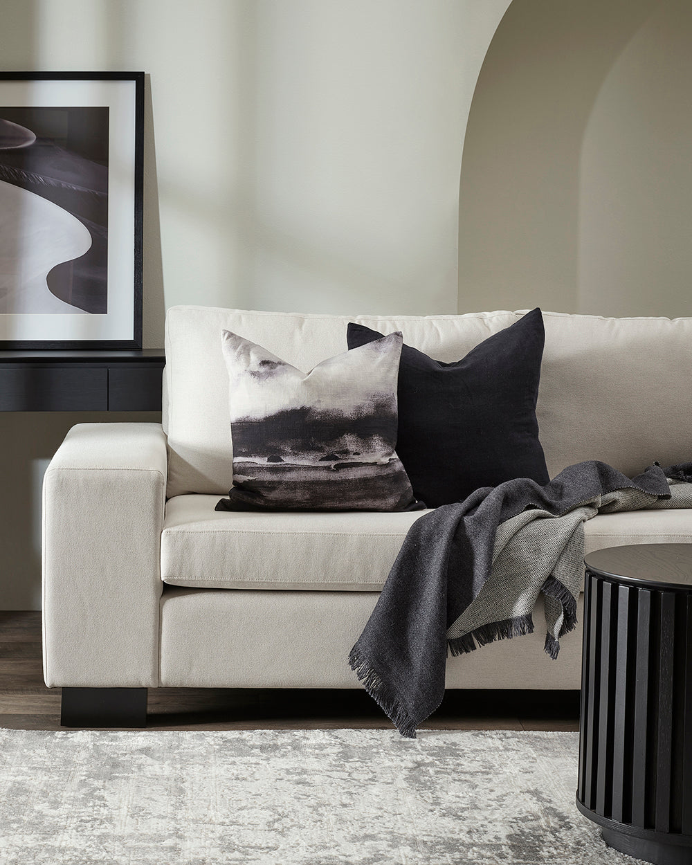 White sofa with decorative pillows and a blanket in a living room setting.