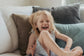 Child laughing on a couch with pillows