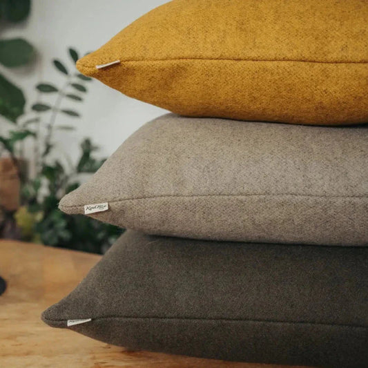 Stack of brown cushions on a wooden surface with a blurred indoor background