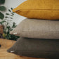 Stack of brown cushions on a wooden surface with a blurred indoor background