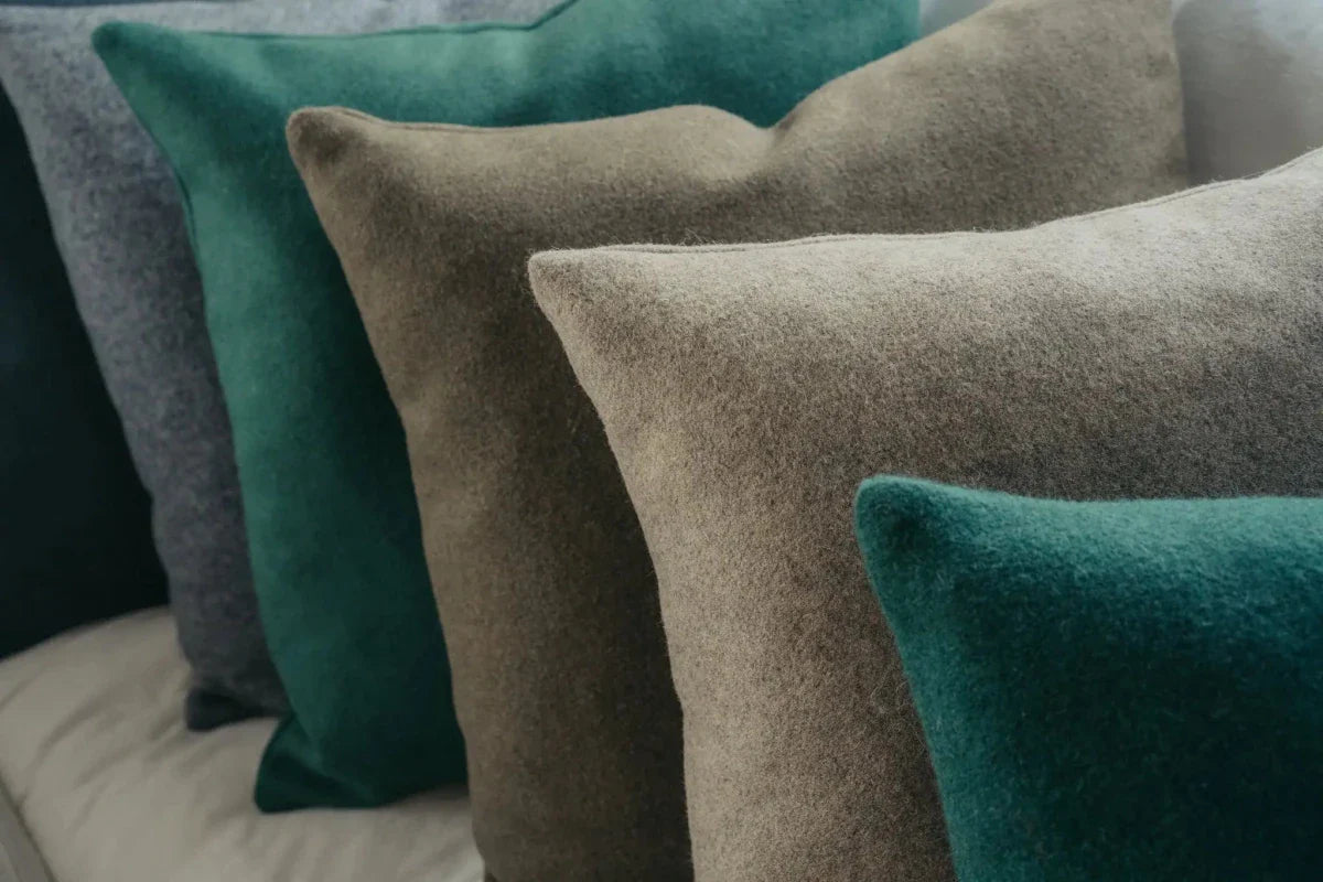 Close-up of textured pillows in green, brown, and gray on a sofa.