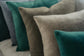 Close-up of textured pillows in green, brown, and gray on a sofa.