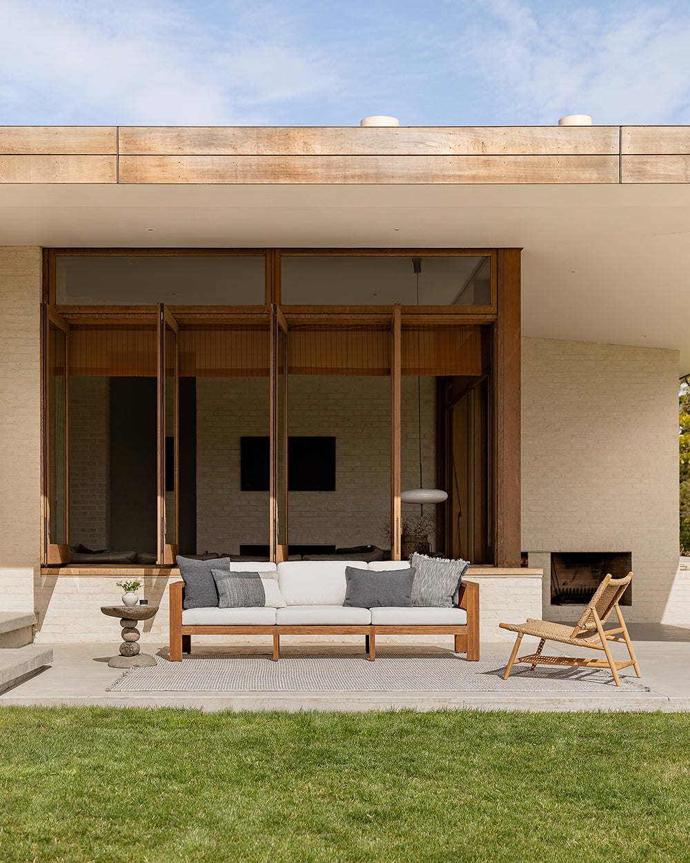 Modern outdoor seating area with a sofa and lounge chair in front of a house.