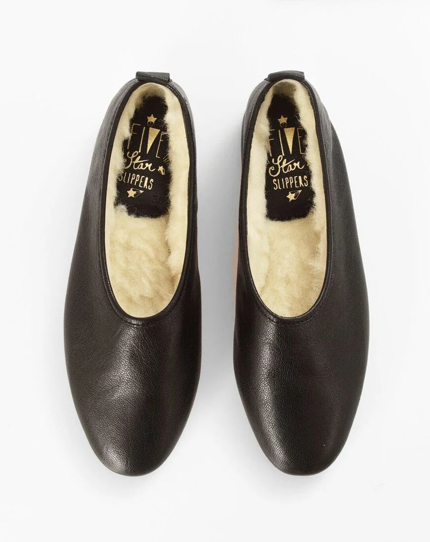 A pair of black  leather slip-on shoes with a cream-colored shearling lining, shown from a top-down view on a white background. The brand name 'Five Star Slippers' is visible on the insole.