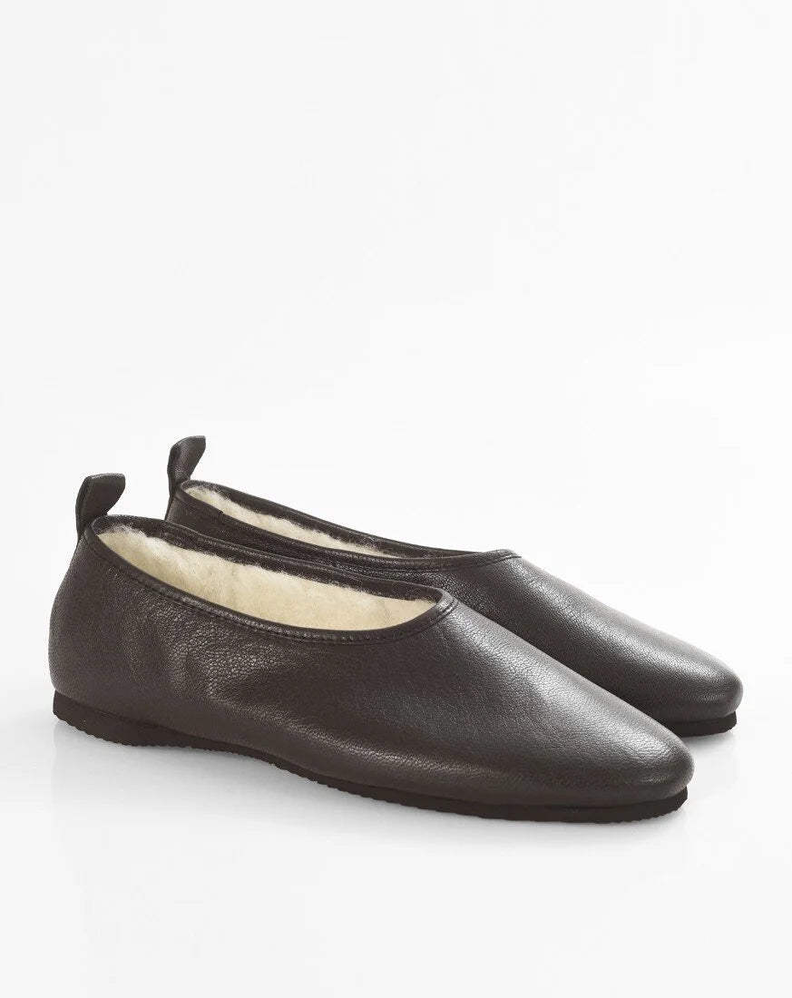 A pair of black  leather slip-on flats with a soft cream-colored lining, displayed on a clean white background.
