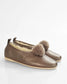 A pair of women's slip-on flats in metallic bronze leather with fluffy brown faux-fur pom-poms on the toe and a cream shearling lining, shown on a white background.