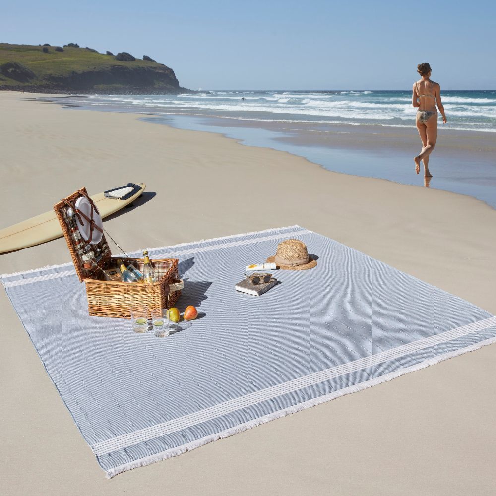 Blue and striped beach blanket with a picnic setting and beach scene