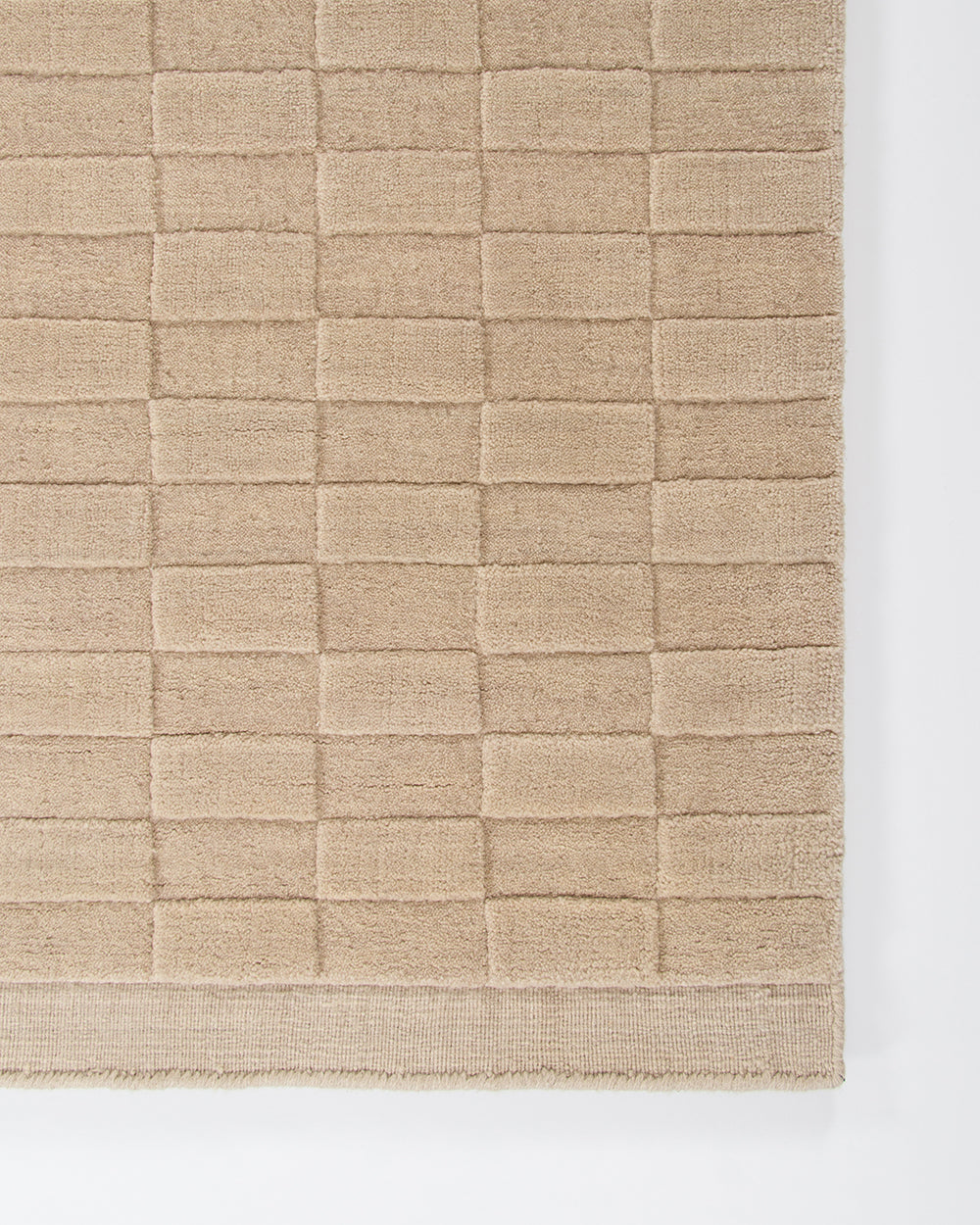 Textured beige rug with a checkered pattern on a white background