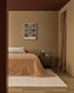 Cozy bedroom with brown bedding, beige walls, and a textured rug.