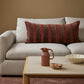 Gray sofa with a striped pillow, wooden coffee table with decorative items, and brown wall.