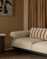 Beige sofa with striped pillow in a room with brown walls and a painting.