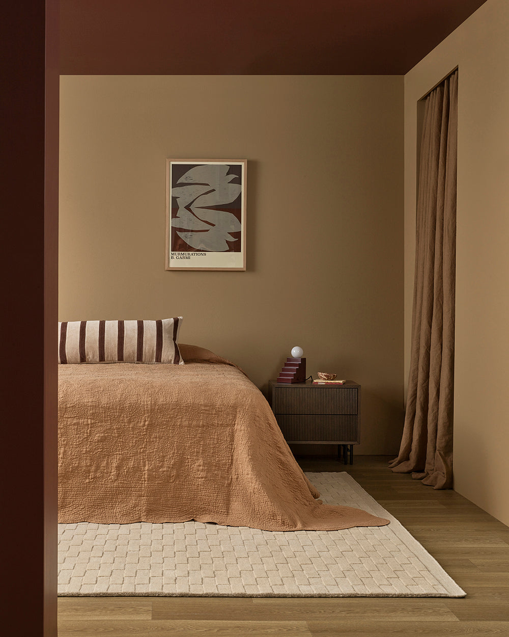 Cozy bedroom with brown bedding, striped pillow, and abstract art on a beige wall.