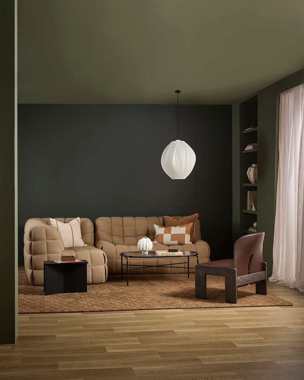 Modern living room with brown sofa, armchair, and coffee table under a white pendant light.