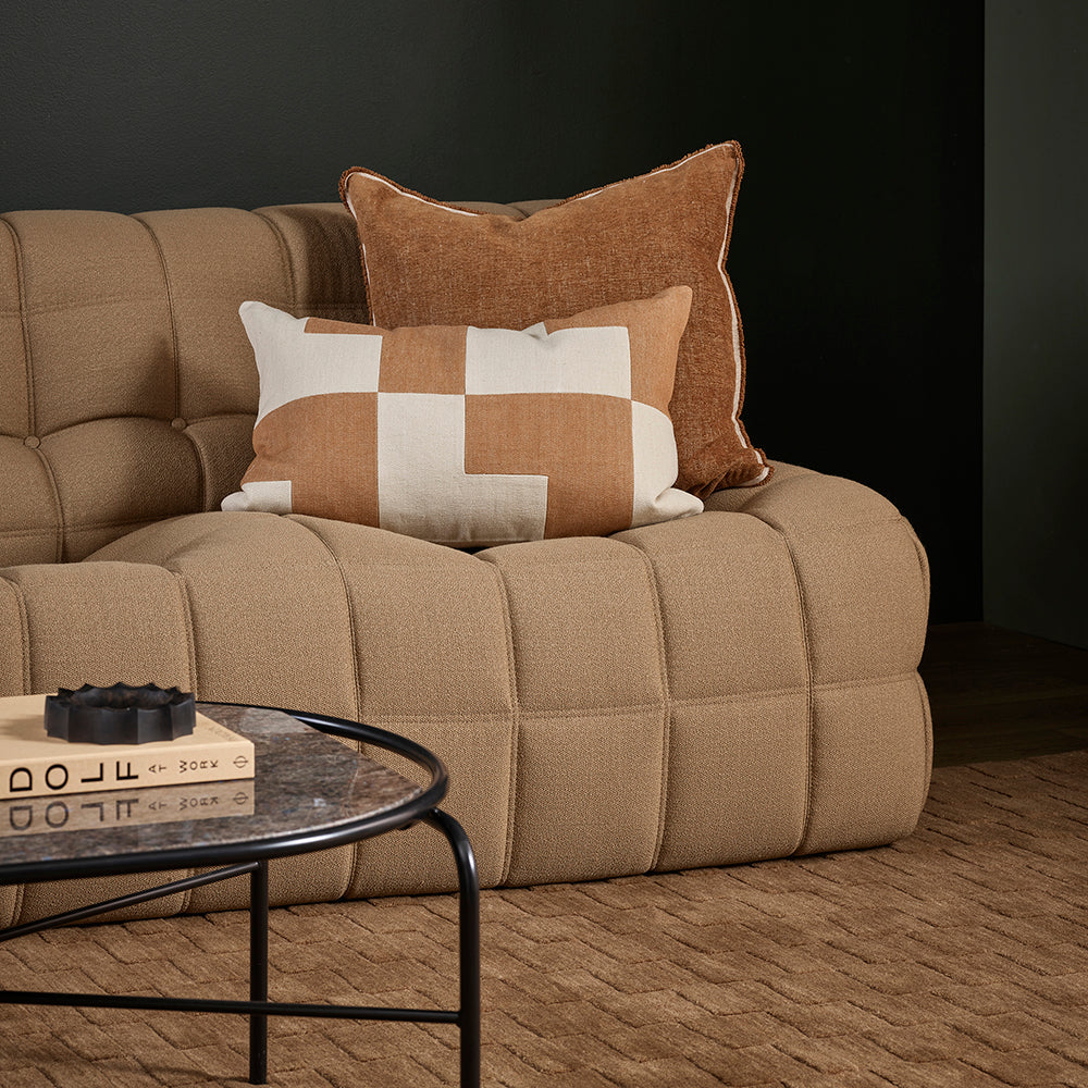 Beige sofa with decorative pillows in a dark room