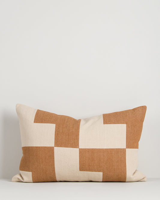 Patchwork pillow with brown and beige squares on a light gray background