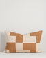 Patchwork pillow with brown and beige squares on a light gray background