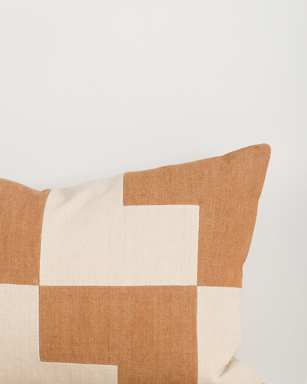 Patchwork pillow with brown and beige squares on a light background