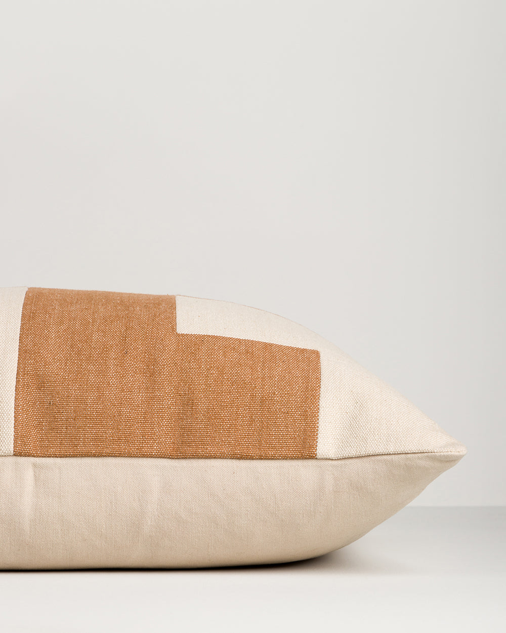 Pillow with brown and beige color block design on a light gray background