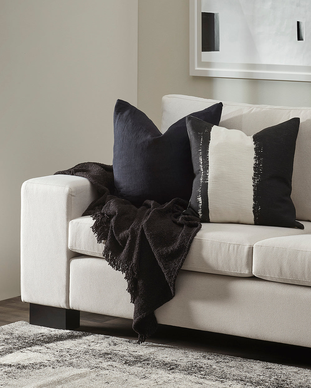 White sofa with decorative pillows and a throw blanket in a living room setting.