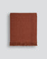 Brown woven blanket with frayed edges on a light gray background