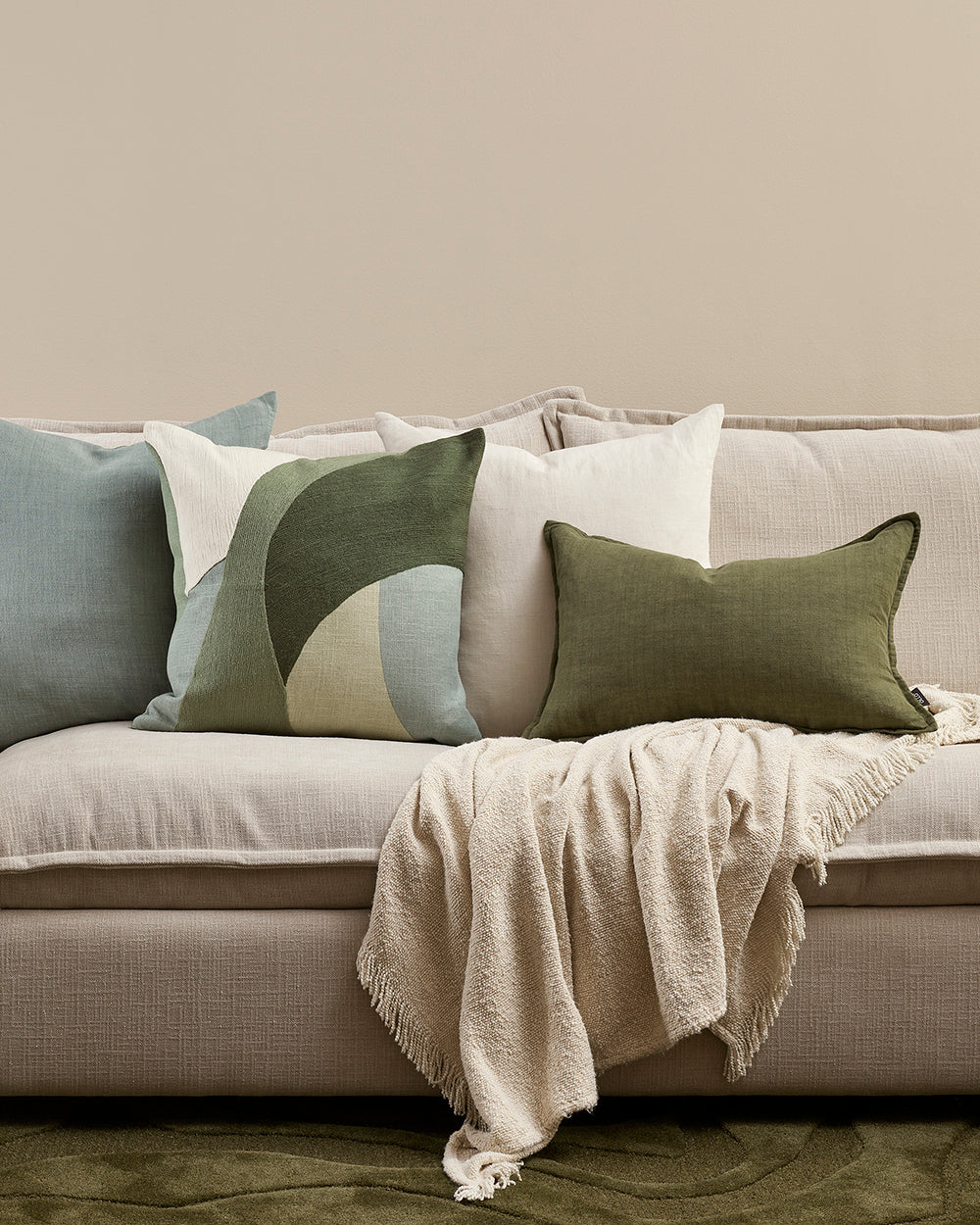 Gray sofa with decorative pillows and a blanket on a neutral background