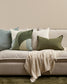 Gray sofa with decorative pillows and a blanket on a neutral background
