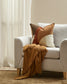Gray sofa with decorative pillows and a brown throw blanket in a living room setting.
