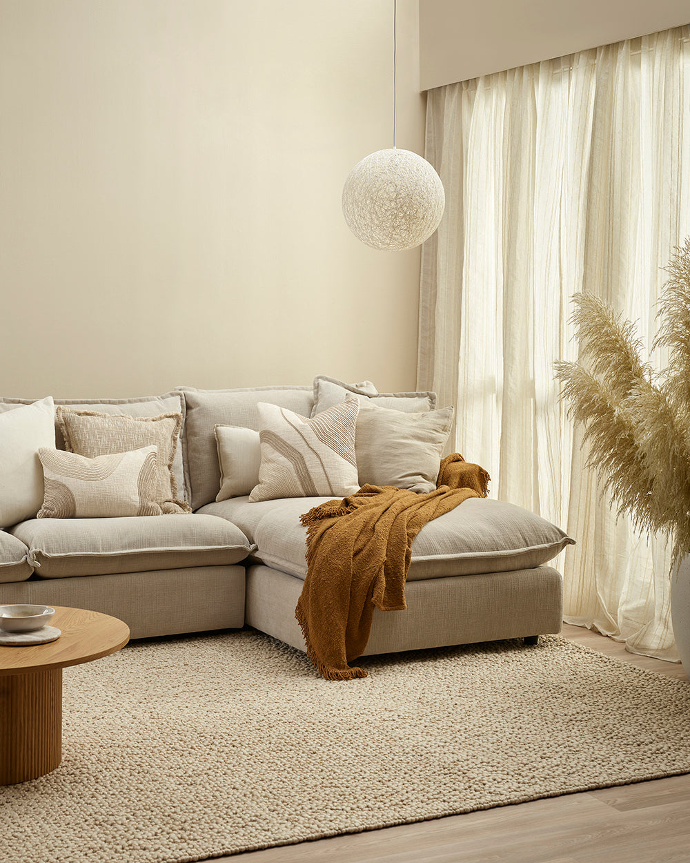 Cozy living room with a beige sectional sofa, cushions, and a small table.