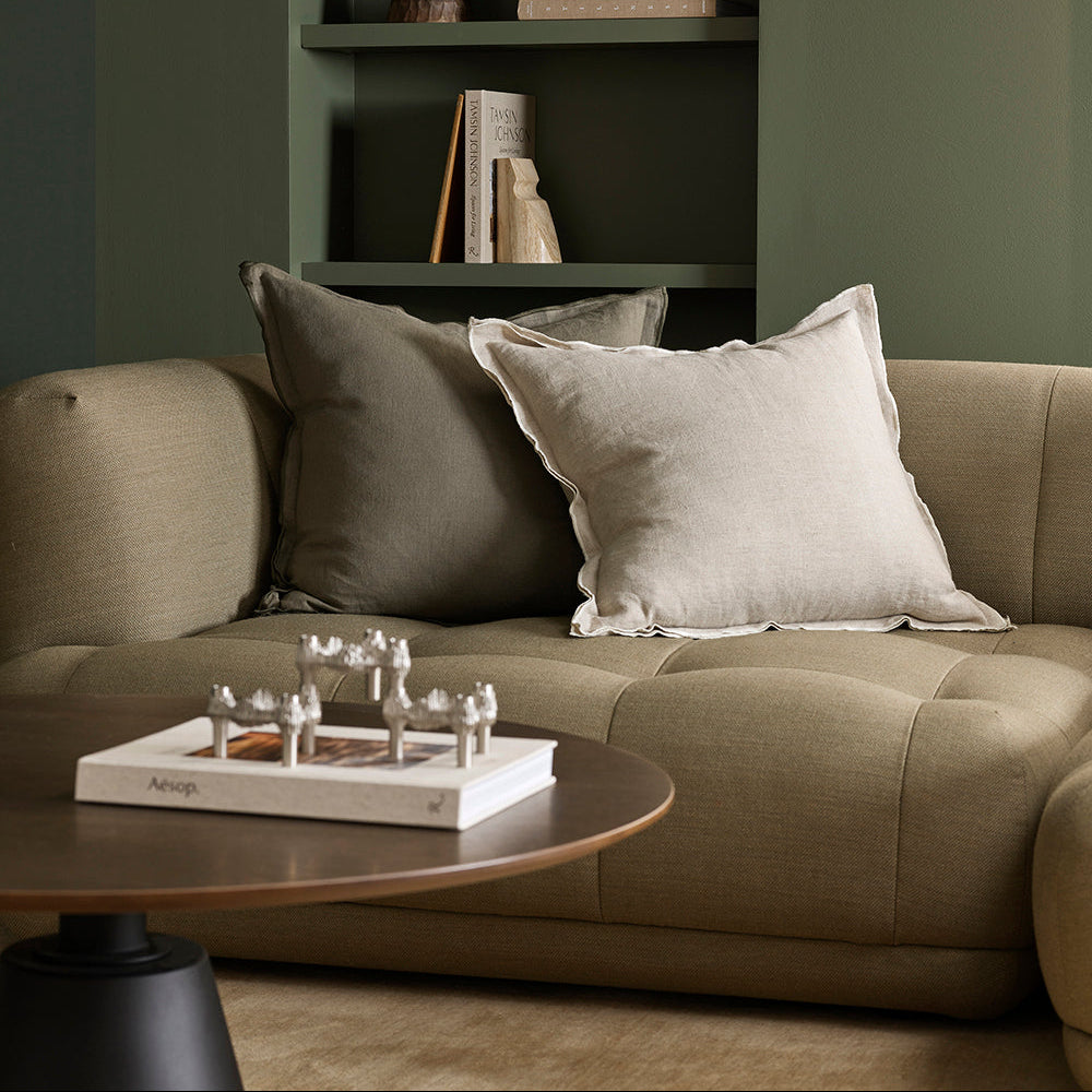 Beige sofa with decorative pillows in a living room setting.