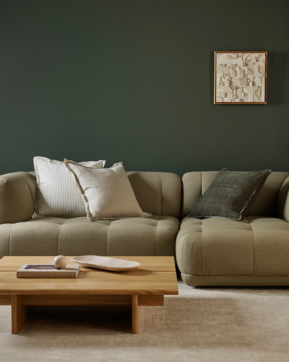 Beige sectional sofa with cushions in a living room setting.