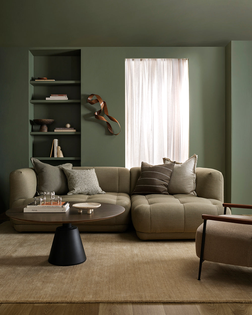 Modern living room with a beige sectional sofa, coffee table, and decorative elements.