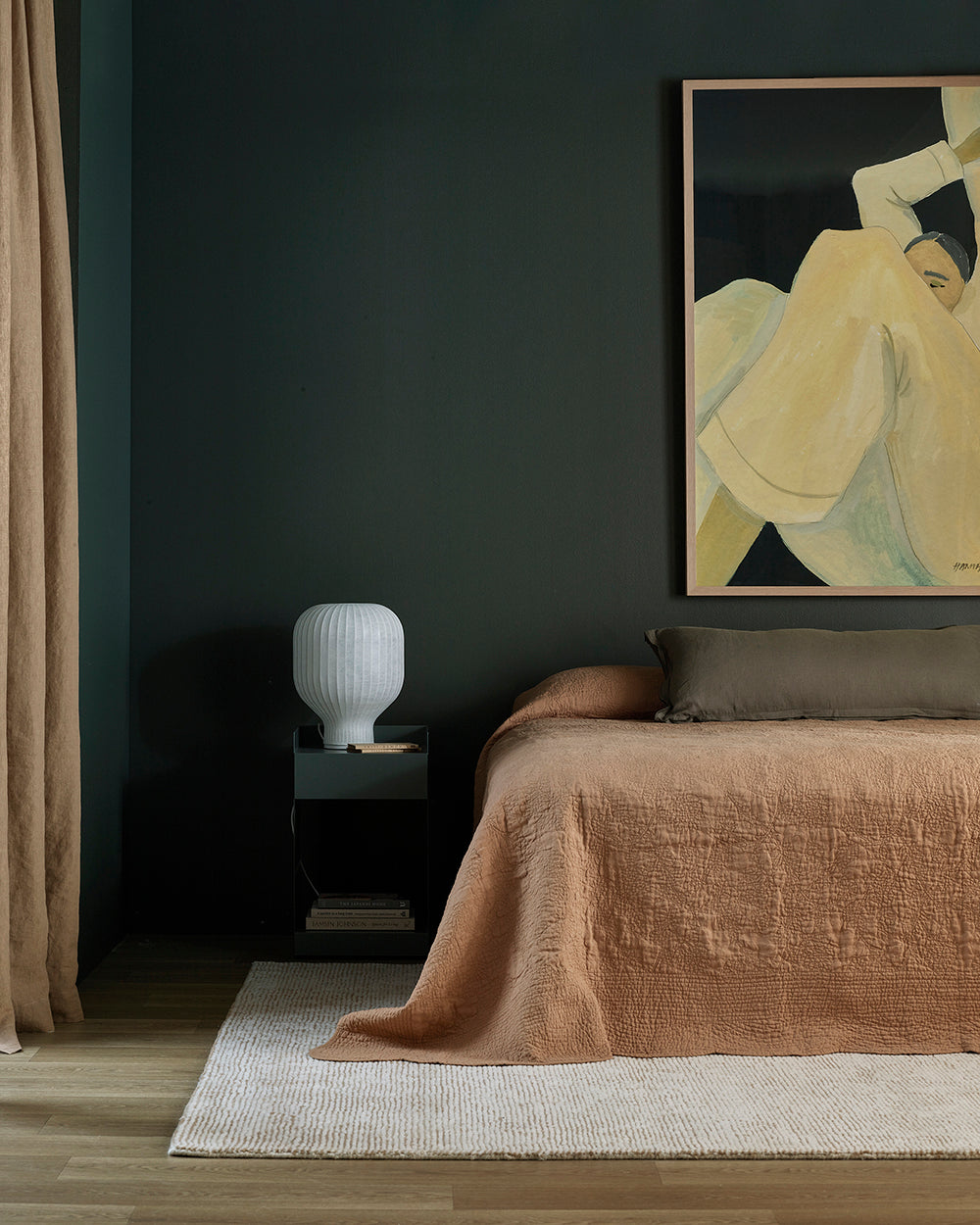 Modern bedroom with dark walls, a bed with brown bedding, and a nightstand with a lamp.
