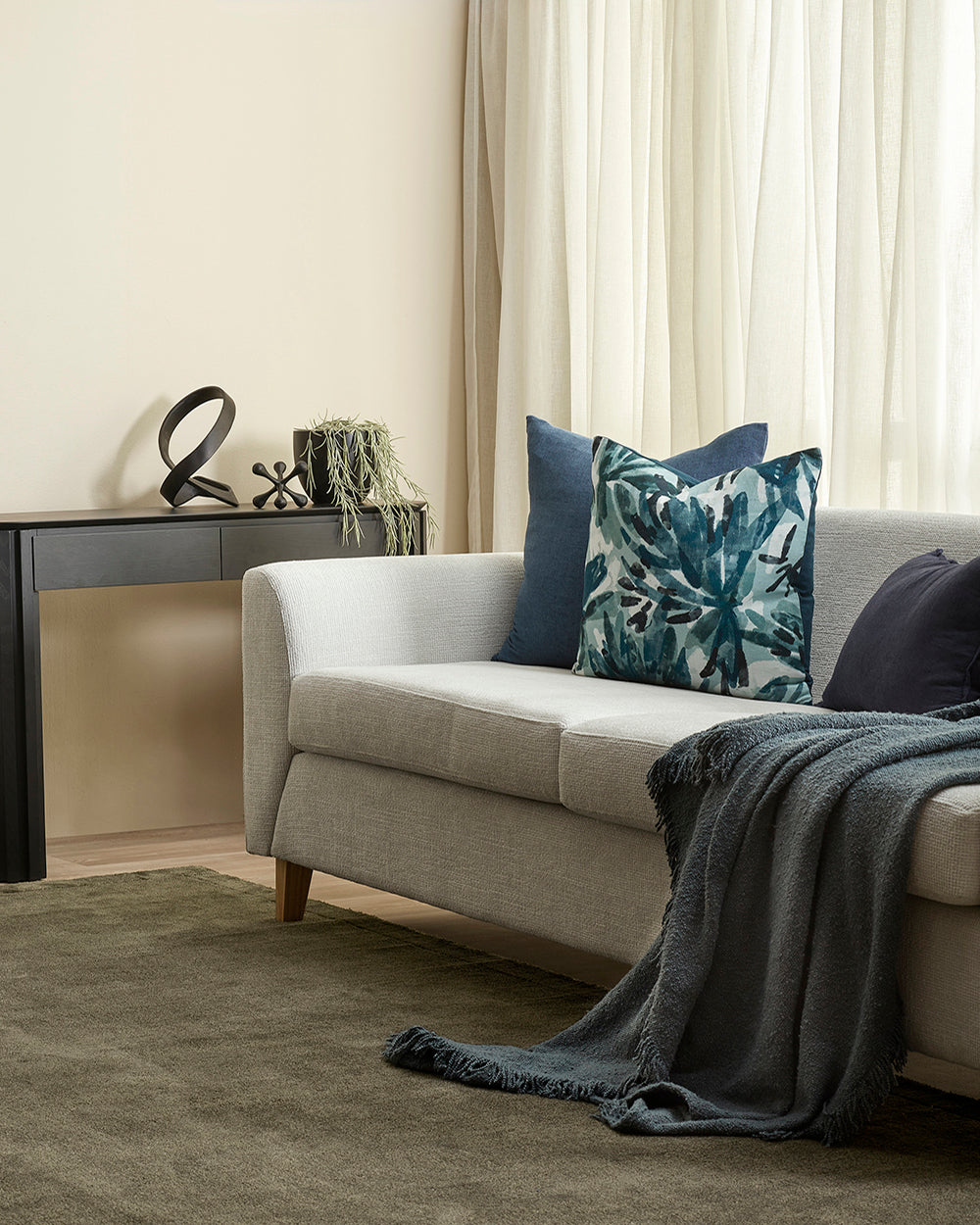 Living room with a beige sofa, decorative pillows, and a side table.