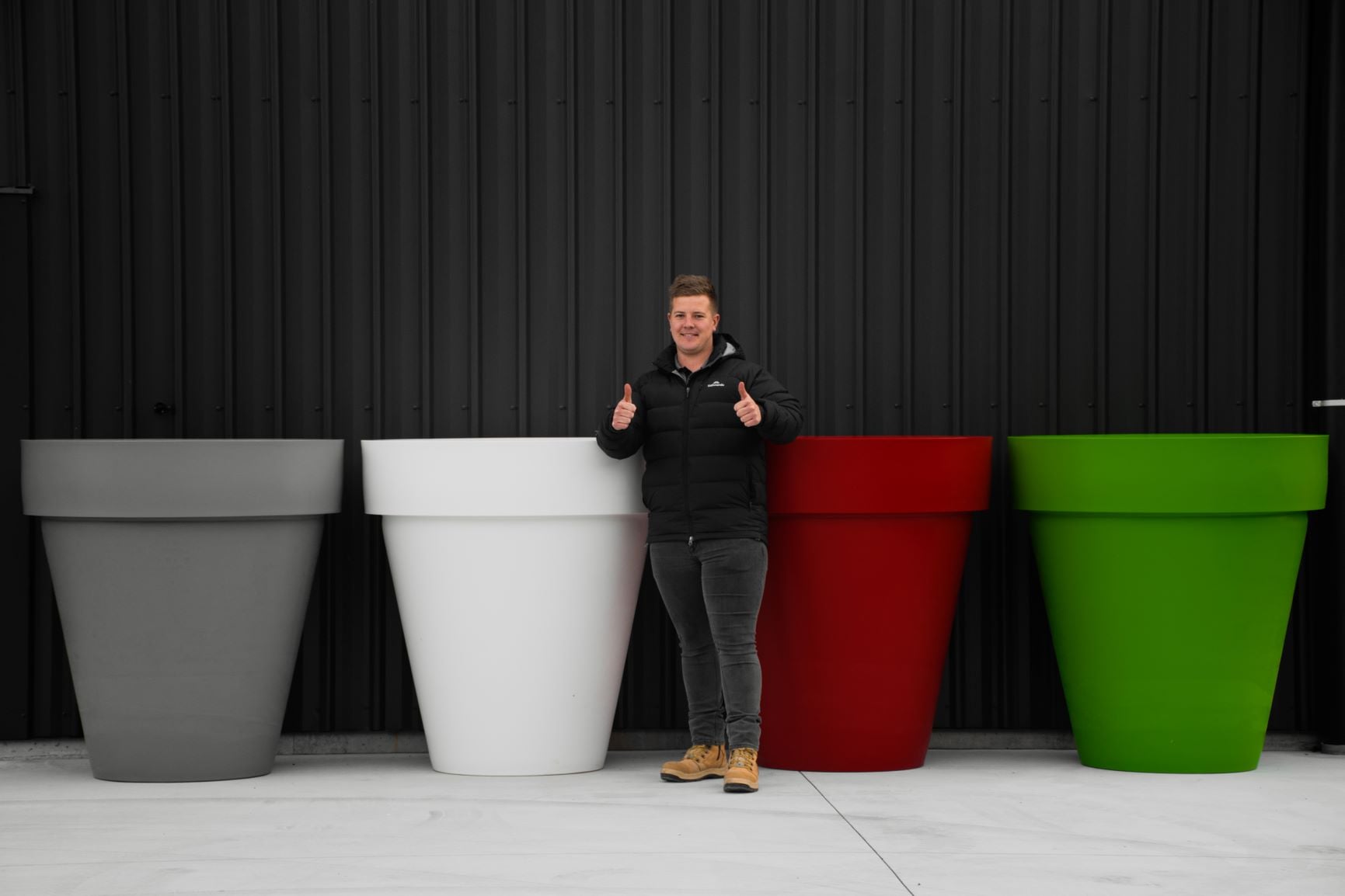 Person standing next to large colorful planters against a black background