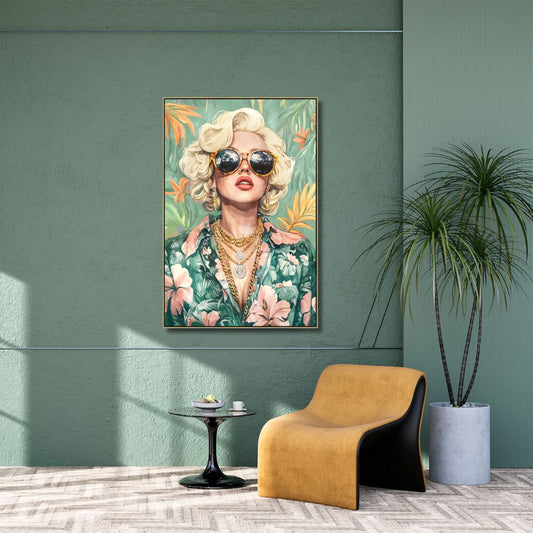 Framed artwork of Marilyn Monroe with sunglasses on a green wall, with a modern chair and plant in the foreground.