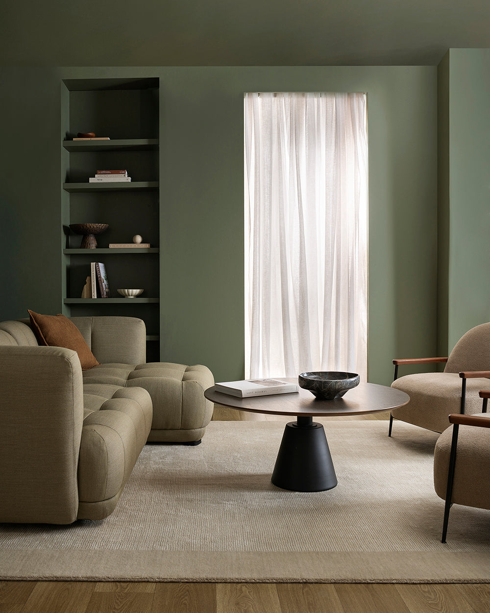 Modern living room with beige sofa, armchair, and round coffee table.