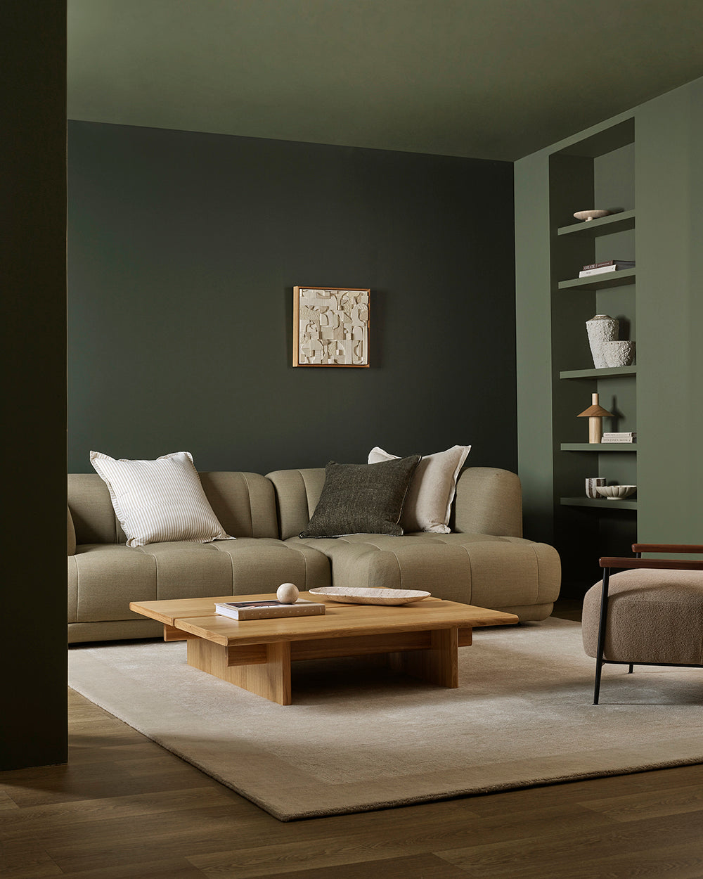 Modern living room with a beige sectional sofa, wooden coffee table, and dark walls.