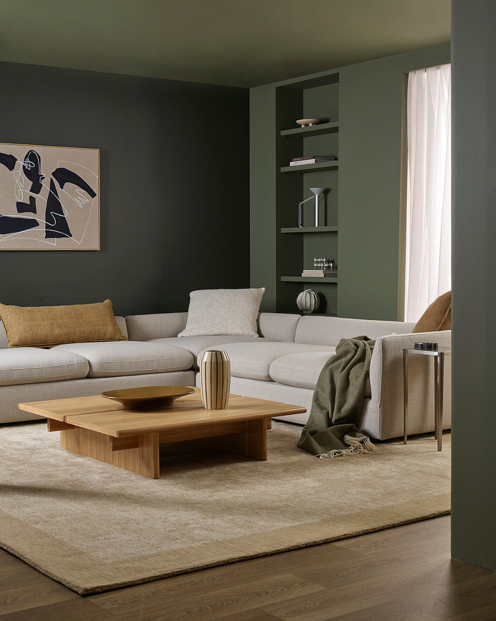 Modern living room with gray sectional sofa, wooden coffee table, and abstract art on wall.