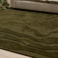 Green textured rug in front of a beige sofa with decorative pillows.